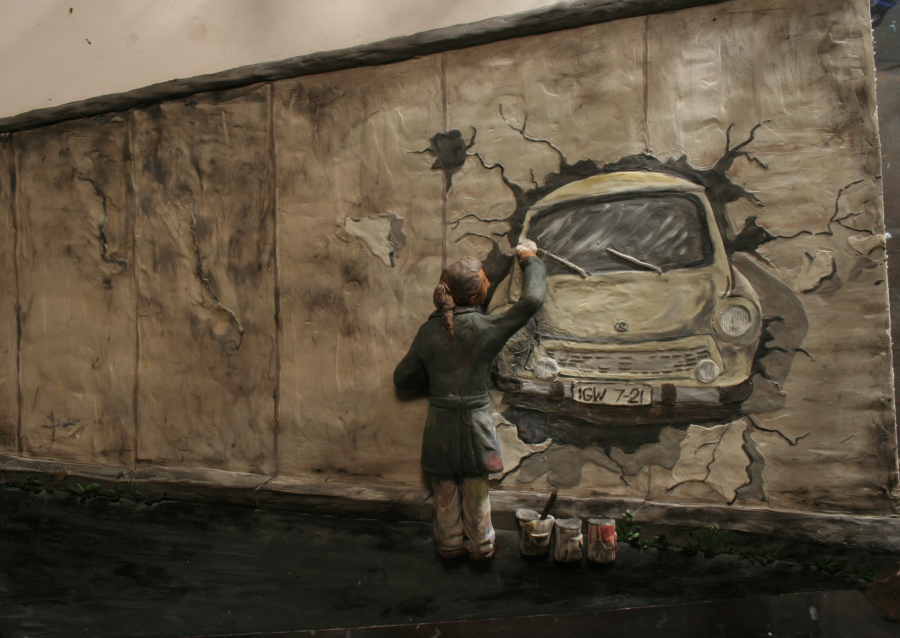 Still von einem Animationsfilm wo eine Person zu sehen ist, die auf die Mauer ein Graffiti von einem Trabi malt.